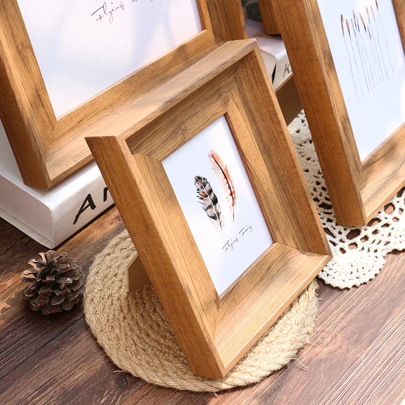 A wooden vintage resin photo frame with a white mat displaying a feather and text, resting on a beige woven coaster.