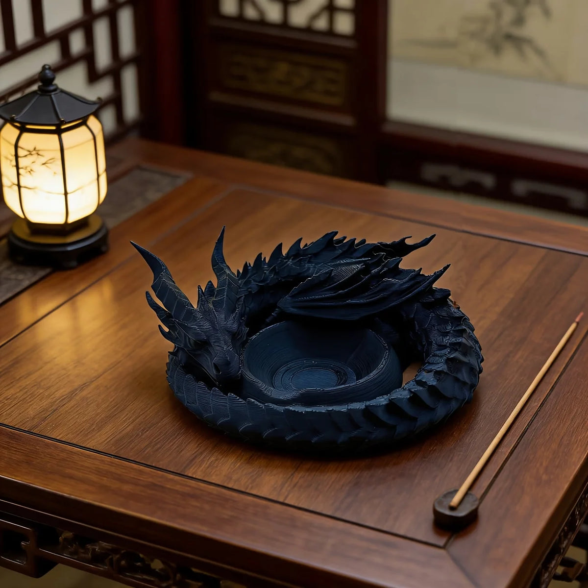 A dark blue dragon-themed desktop storage tray organizer resting on a wooden table next to an illuminated lantern.