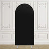 Un arco de fondo de tela negra oval y alta, exhibido contra una pared blanca con molduras decorativas.