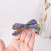 A hand holds a sparkling natural crystal tourmaline dragonfly figurine with iridescent blue and purple colors.