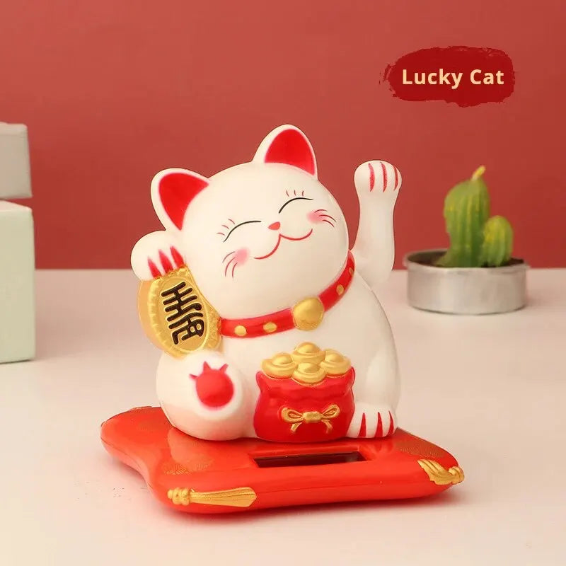 A white ceramic cat with a red nose and waving arm sits on an orange solar-powered platform.