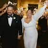 A bride and groom are joyfully waving LED glow wands with ribbons and bells during a wedding celebration.
