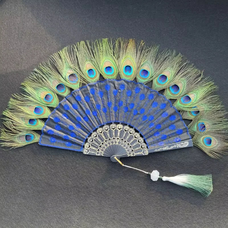 Un éventail à main fait d'une plume de paon naturelle avec des plumes vertes et bleues irisées, affiché sur un fond sombre.