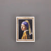 A framed painting featuring a woman wearing a purple and yellow headscarf against a dark background.