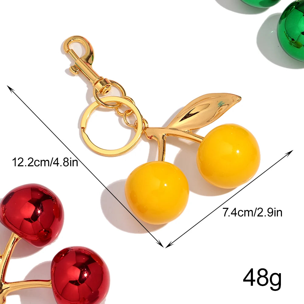 Gold-colored resin pendant keychain featuring a yellow spherical charm and a red spherical charm.