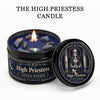 A dark candle jar labeled High Priestess with crystal stones and a lit wick, next to an open lid.