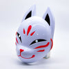 A white fox face mask with black and red accents, displayed on a clear stand.
