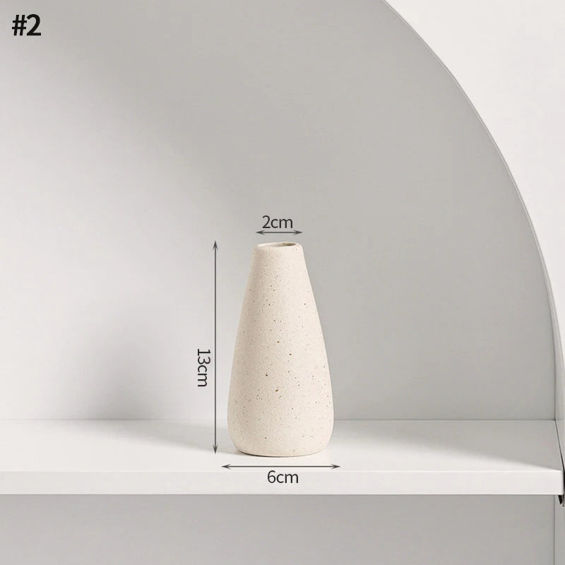 A tall, tapered beige ceramic vase displayed on a white shelf.