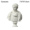 A white plaster bust miniature of a classical Greek figure with curly hair and draped clothing.