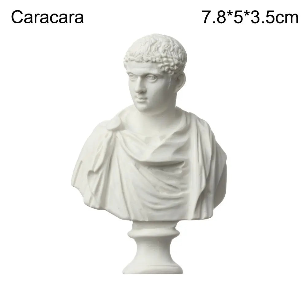 A white plaster bust miniature of a classical Greek figure with curly hair and draped clothing.