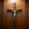 Hand carved wooden cross wall decor with a silver crucifix mounted on a wooden door panel.