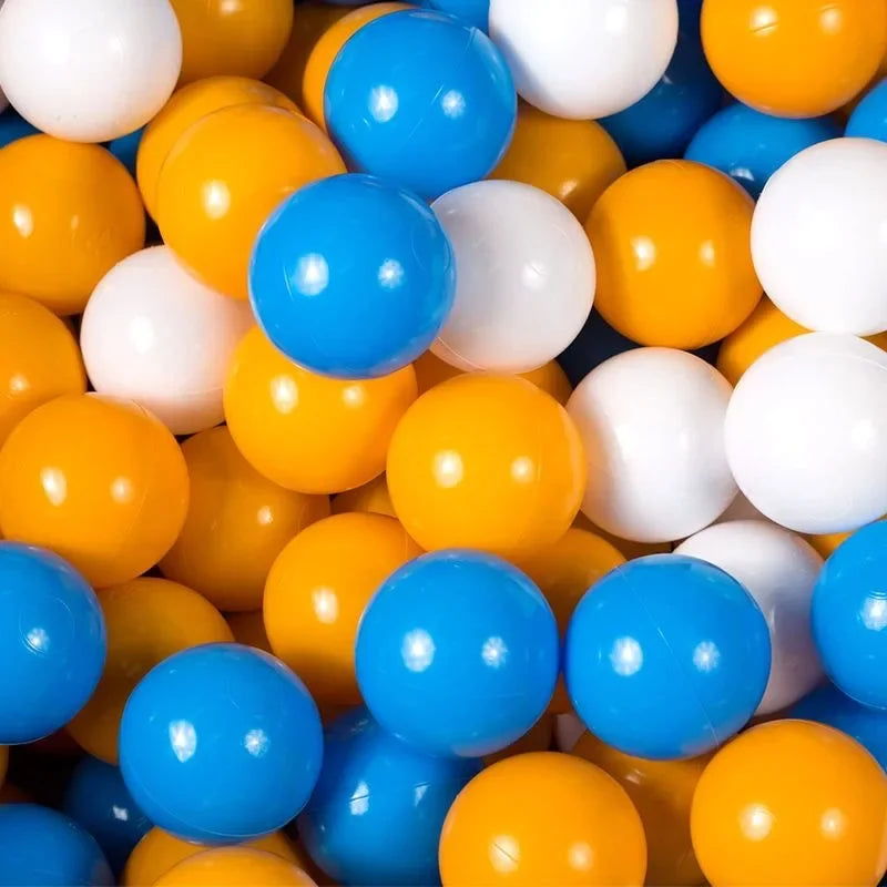 A pile of colorful, shiny plastic balls in yellow, white, and blue for kids' play.