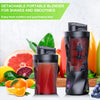 A black portable blender jar filled with red juice sits next to fresh citrus fruits and blueberries.