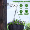 A hanging plants bracket with a wrought iron vine supports a potted plant against a wooden post.