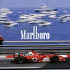 A vintage Formula 1 car in red is shown racing on a track with blurred boats in the background.