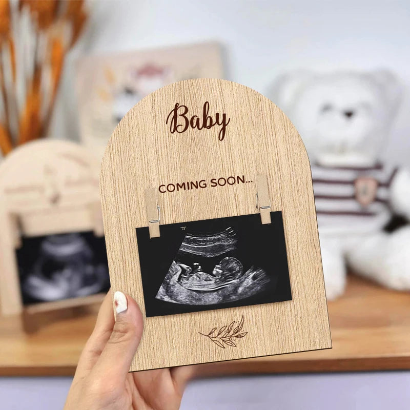 A wooden pregnancy announcement photo frame displaying an ultrasound image.