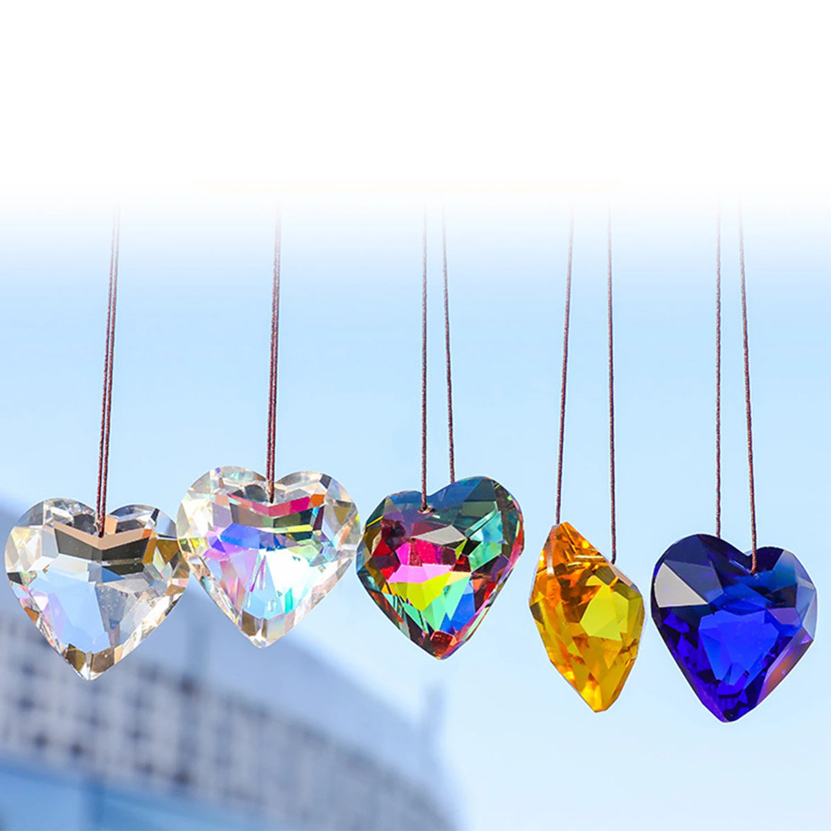 A collection of heart-shaped glass pendants with iridescent rainbow colors hanging from thin strings.