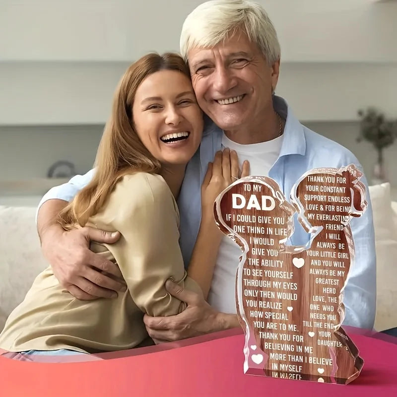 A smiling man and woman hugging, posing with an acrylic tabletop sign for dad.