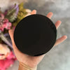 A hand holds a round, black obsidian mirror for Feng Shui and divination.
