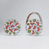 Silver handbag hook with a floral crystal design featuring red, green, and blue elements.