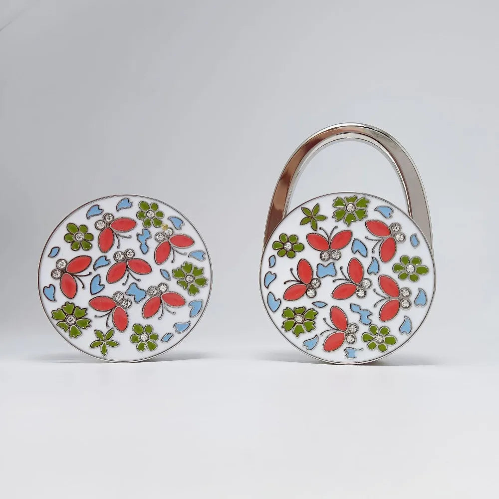 Silver handbag hook with a floral crystal design featuring red, green, and blue elements.