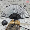 An elegant vintage Chinese folding hand fan with black and gray stripes is displayed on a wooden stand.