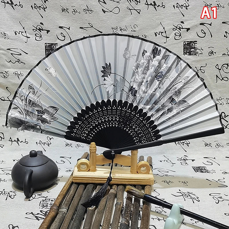 An elegant vintage Chinese folding hand fan with black and gray stripes is displayed on a wooden stand.