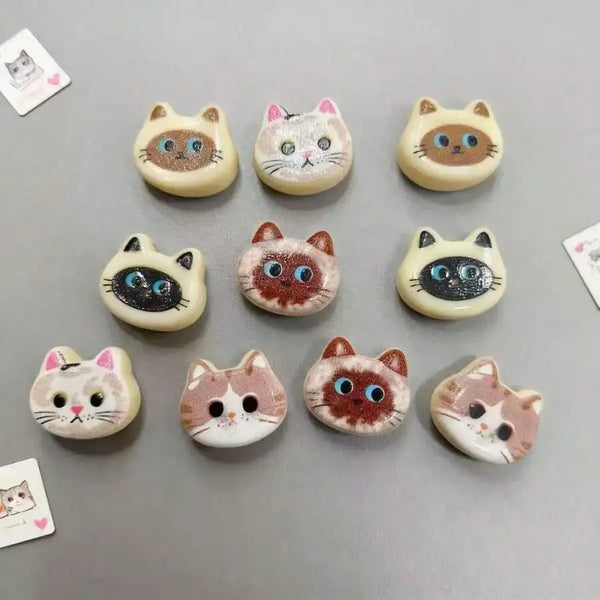A set of ten adorable cat head fridge magnets in various colors and styles for kitchen and home decor.