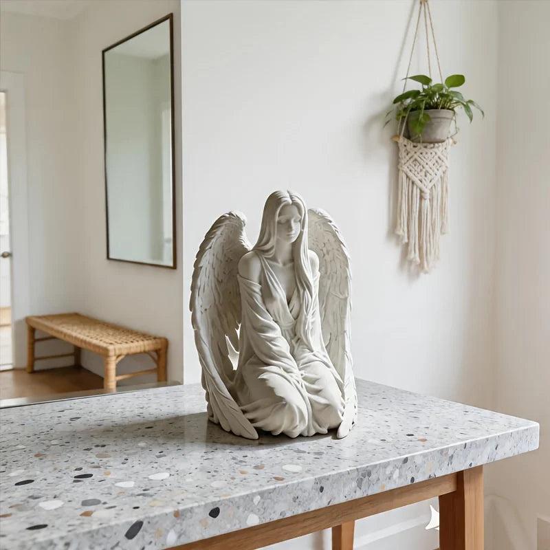 Estatua de ángel de mármol blanco con alas exhibida en una mesa de madera.
