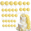 A set of yellow foam cake toppers displayed on white sticks and a white cake.
