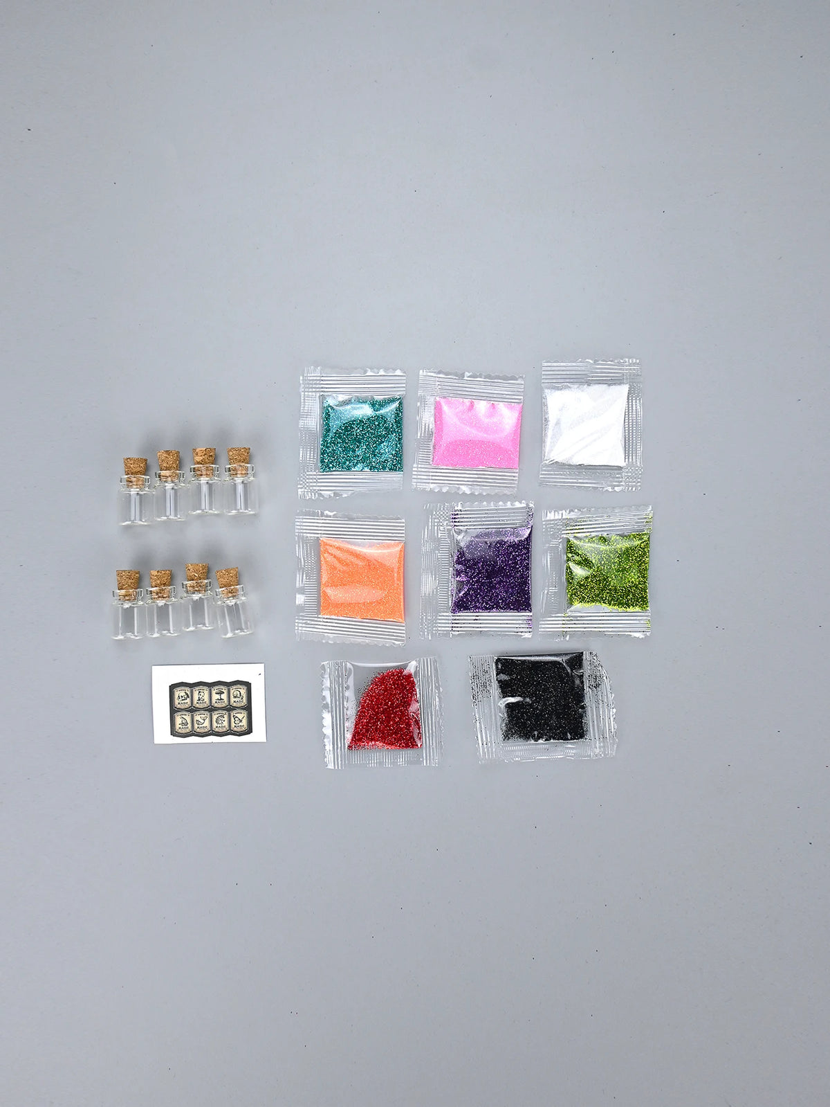 A collection of various colored glitter powders in small plastic packets for party decorations.