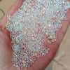 A hand holds a scattering of iridescent nail rhinestones for DIY art.