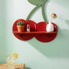 A wooden shelf shaped like a cherry, mounted on a light green wall, holding potted plants and white ceramic items.
