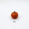 A small, round, orange velvet pumpkin decoration with a stem, shown against a white background.