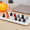A white rectangular platter holds a set of twelve mini resin Halloween duck figurines in various colors and shapes.