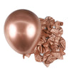 A single, shiny rose gold latex balloon is shown next to a pile of crumpled rose gold metallic foil balloons.