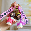 A hand holds a silicone Jesus keychain featuring a pink strap and a figure with a purple robe.