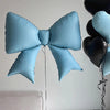 Light blue bow-shaped foil balloon decoration hanging against a white wall.