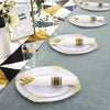 Elegant white and gold disposable dinnerware set with cutlery arranged on a gray table.