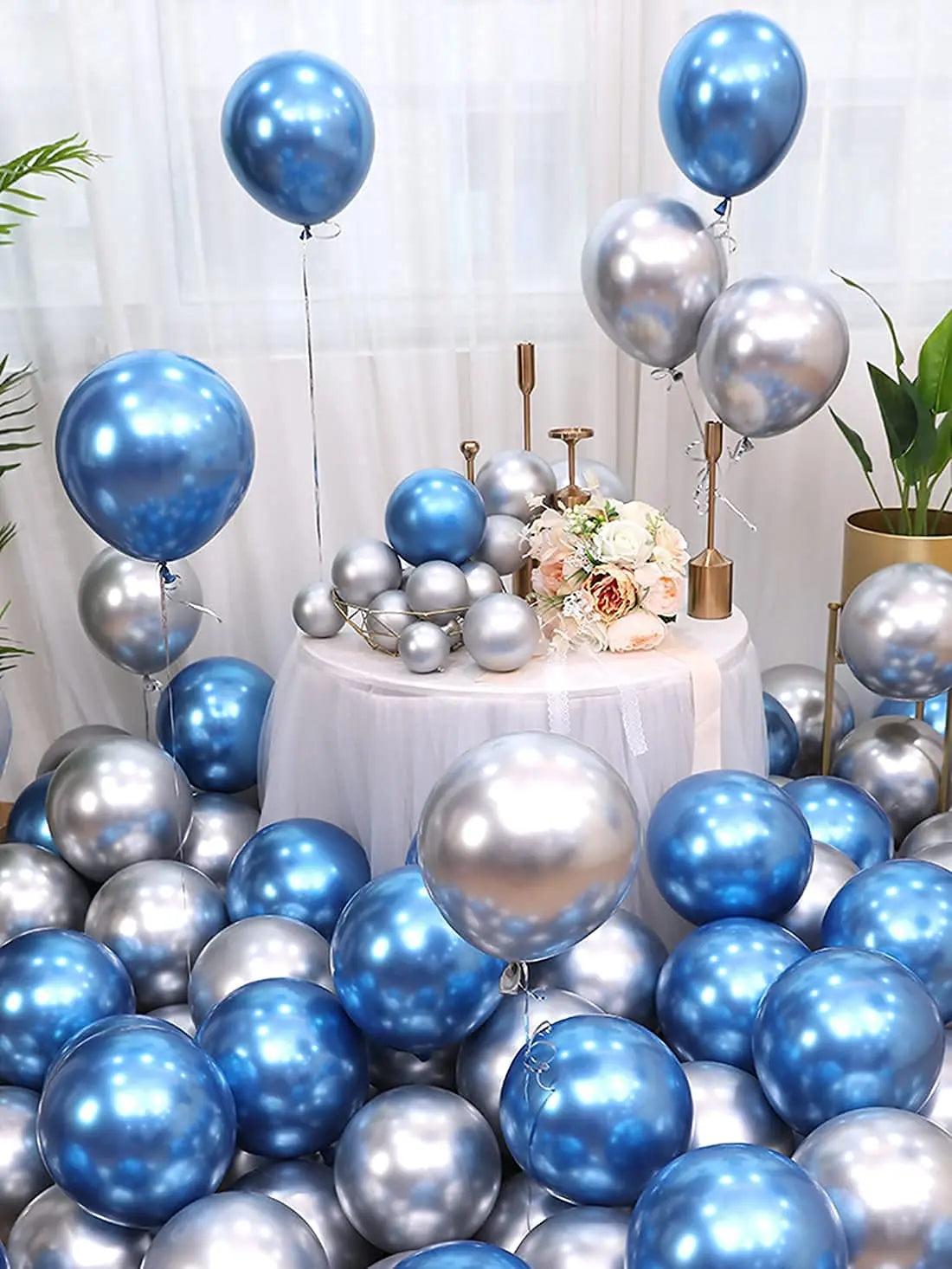A collection of chrome metallic blue and silver balloons arranged on a table with floral decorations.