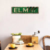 Vintage metal tin sign with green background and red stripes spelling out ELM St.
