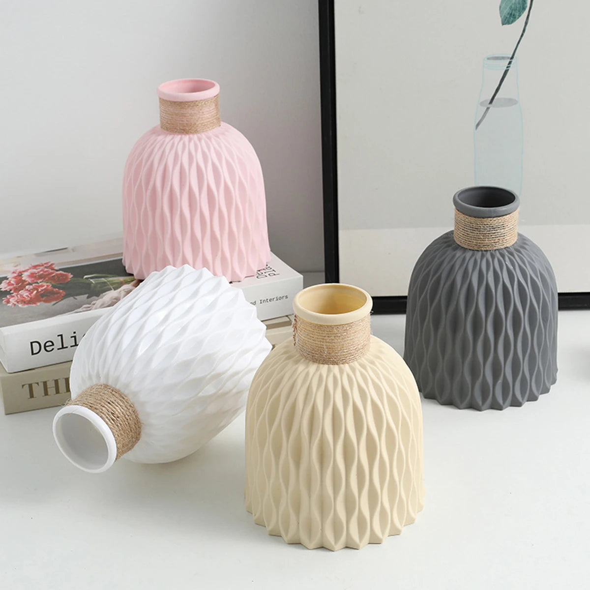 Three ceramic vases in pink, gray, and cream with a textured ripple pattern displayed on a white surface.
