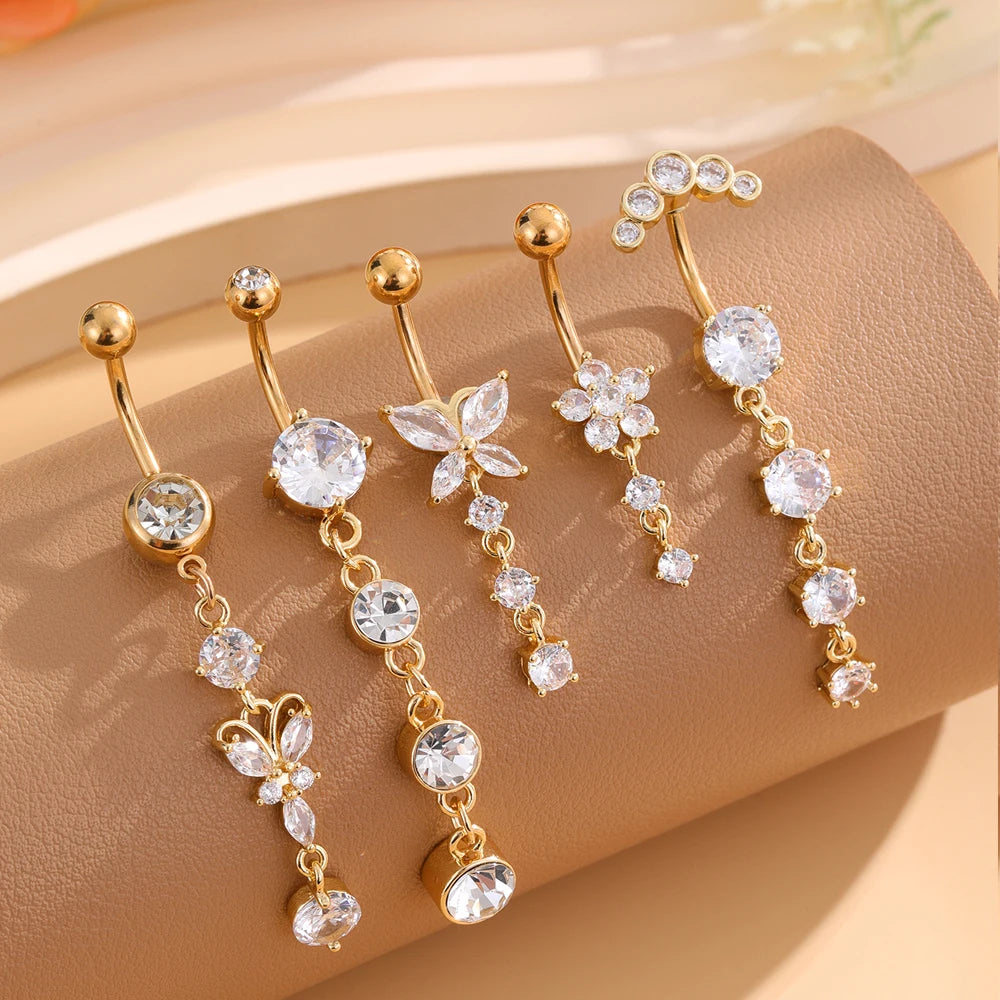 A set of five gold tone butterfly and flower belly rings displayed on a neutral background.