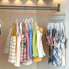Wall-mounted metal coat rack displaying various colorful knitted and woven garments on hooks