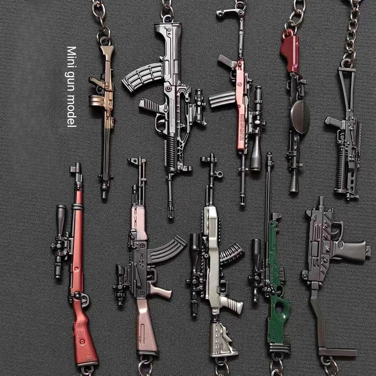 A collection of realistic miniature gun models on keychains, featuring various firearms in different colors and styles.