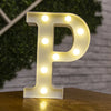 A glowing warm white LED alphabet letter light shaped like the letter P resting on a wooden surface.