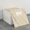 A stack of self-adhesive marble tile stickers showing a beige and brown veined pattern on a gray floor.