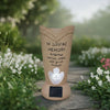 A terracotta vase shaped like a stylized leaf holds a small LED light, used for a solar grave memorial.