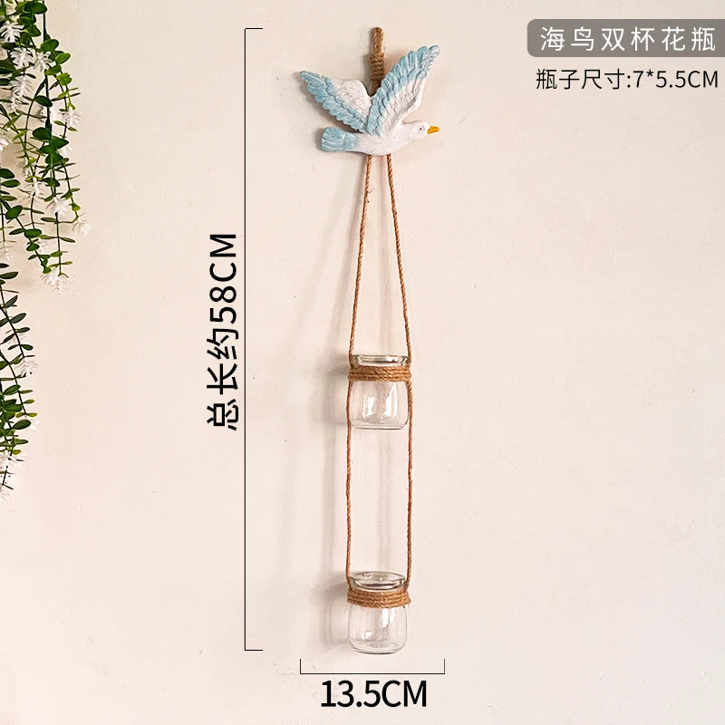 A decorative glass terrarium with a blue and white bird figurine suspended by twine.