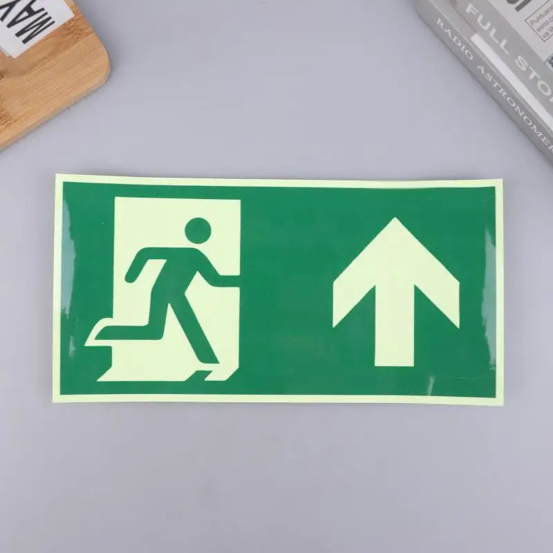 A rectangular photoluminescent emergency exit sign decal with a silhouette of a person running and an upward arrow on a green